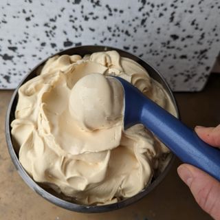 Foto van een scheplepel in een pot met gezouten karamel